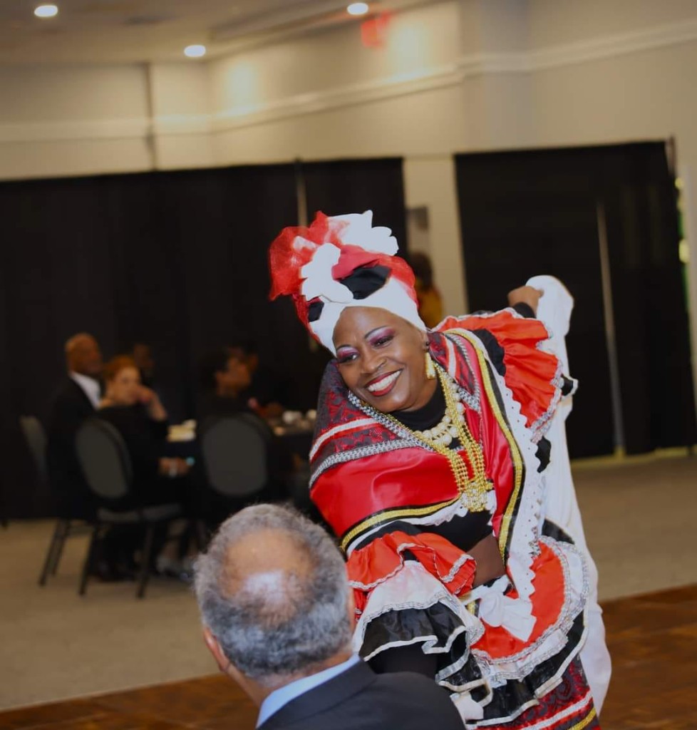 Performer in a vibrant red, white, and black ruffled dress dancing for guests at the Scholarship Gala